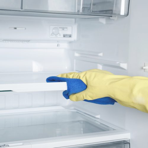 Employees use a cloth to clean the refrigerator.
